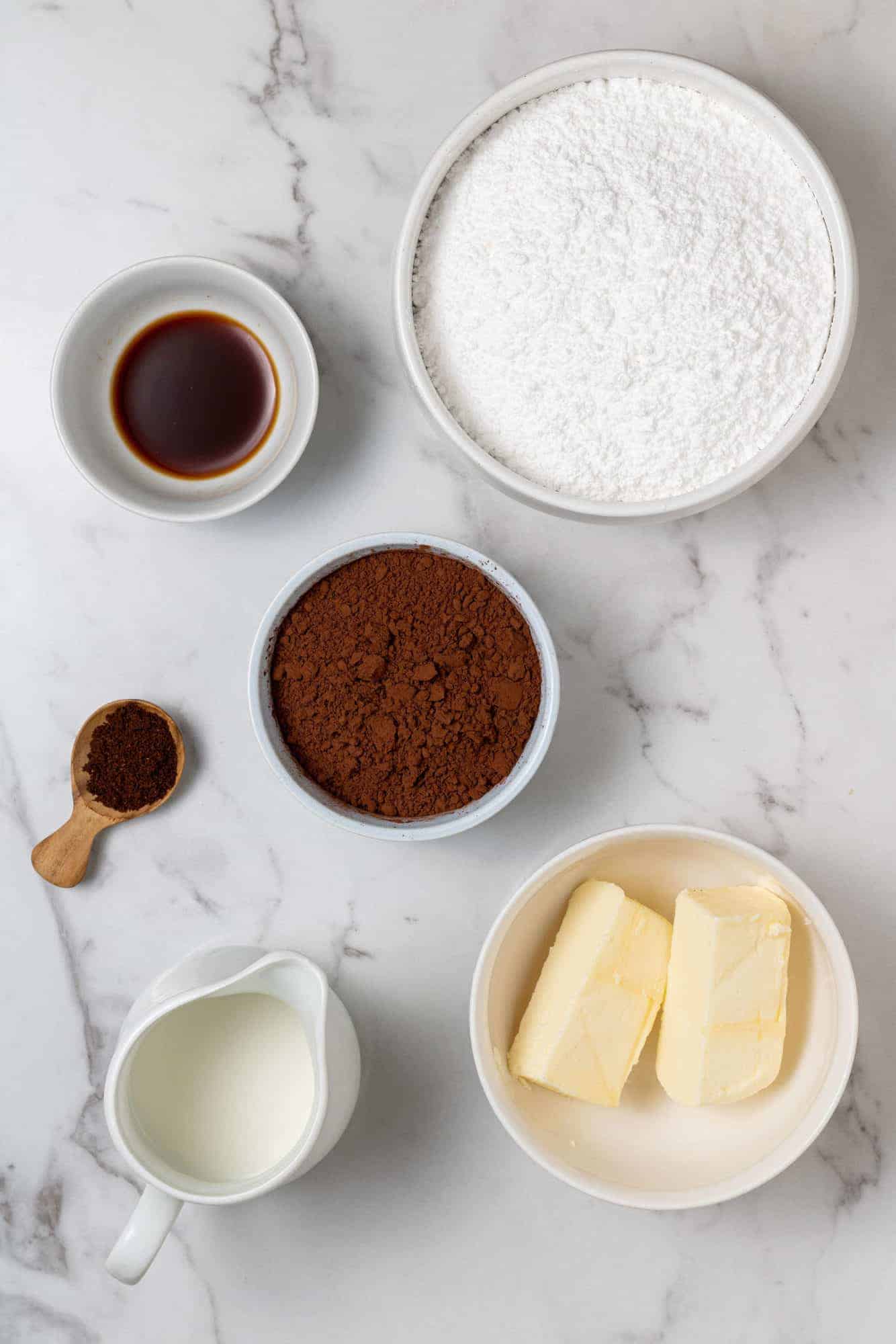 Overhead view of ingredients needed: powdered sugar, cocoa powder, butter, milk, espresso powder, vanilla.