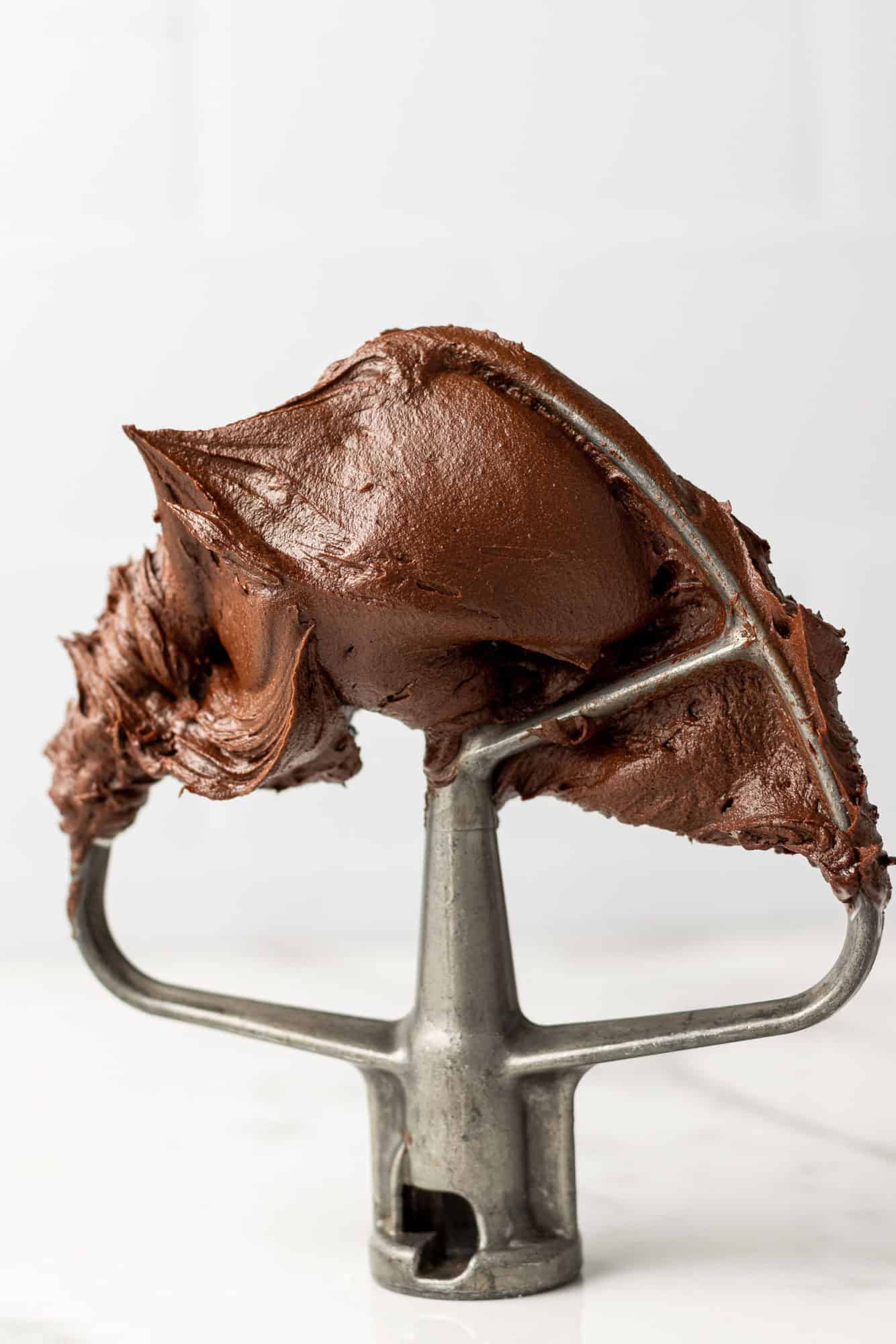 Chocolate buttercream frosting on a mixer beater.