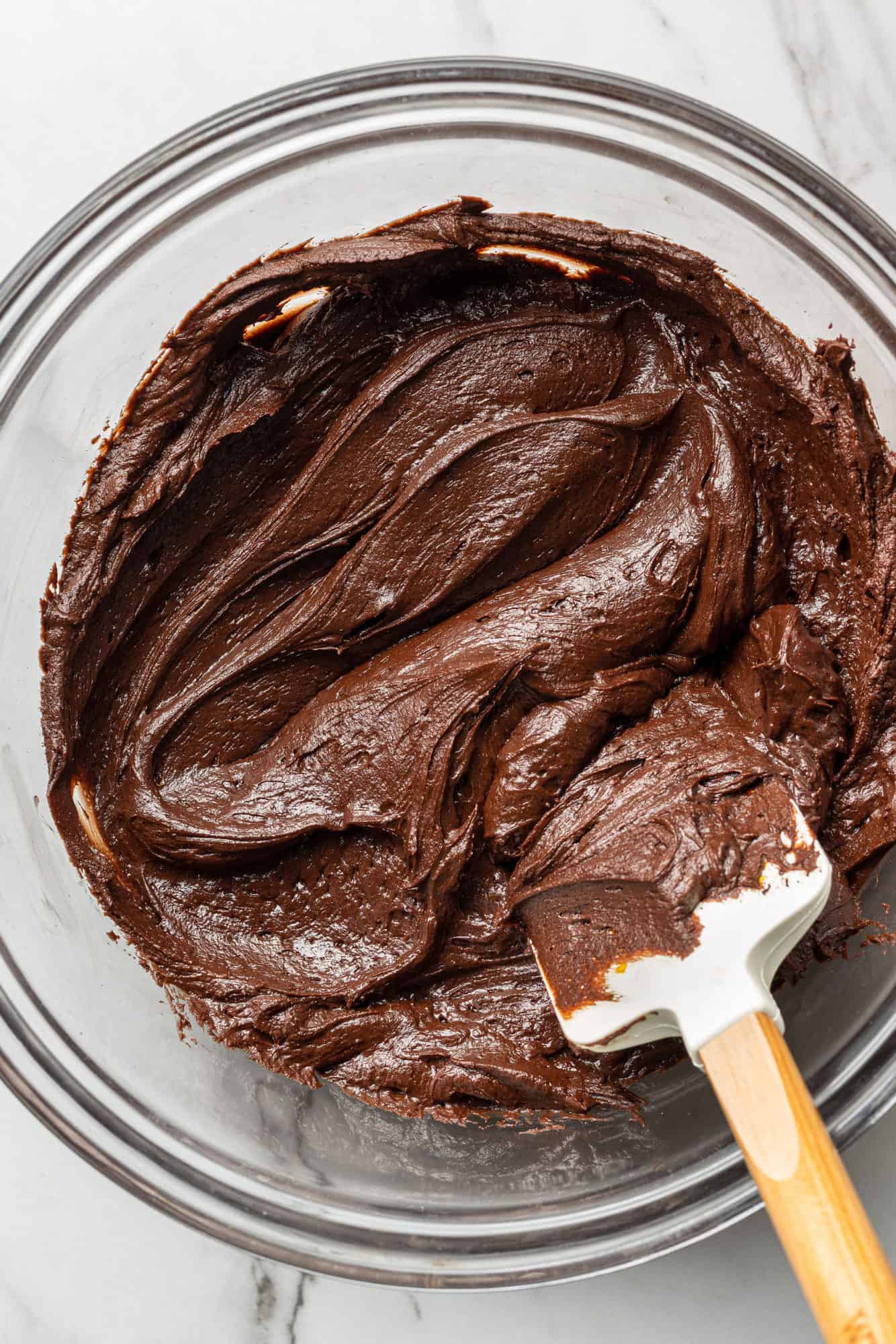 Chocolate frosting in a bowl with a spatula.