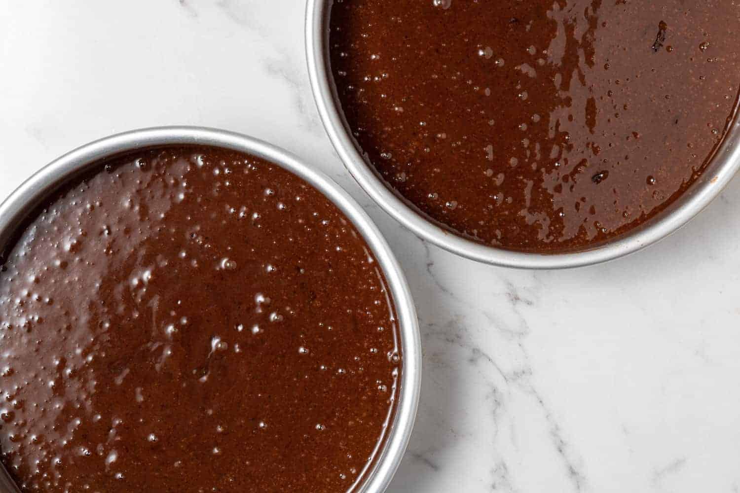 Unbaked cake in two round metal cake pans.