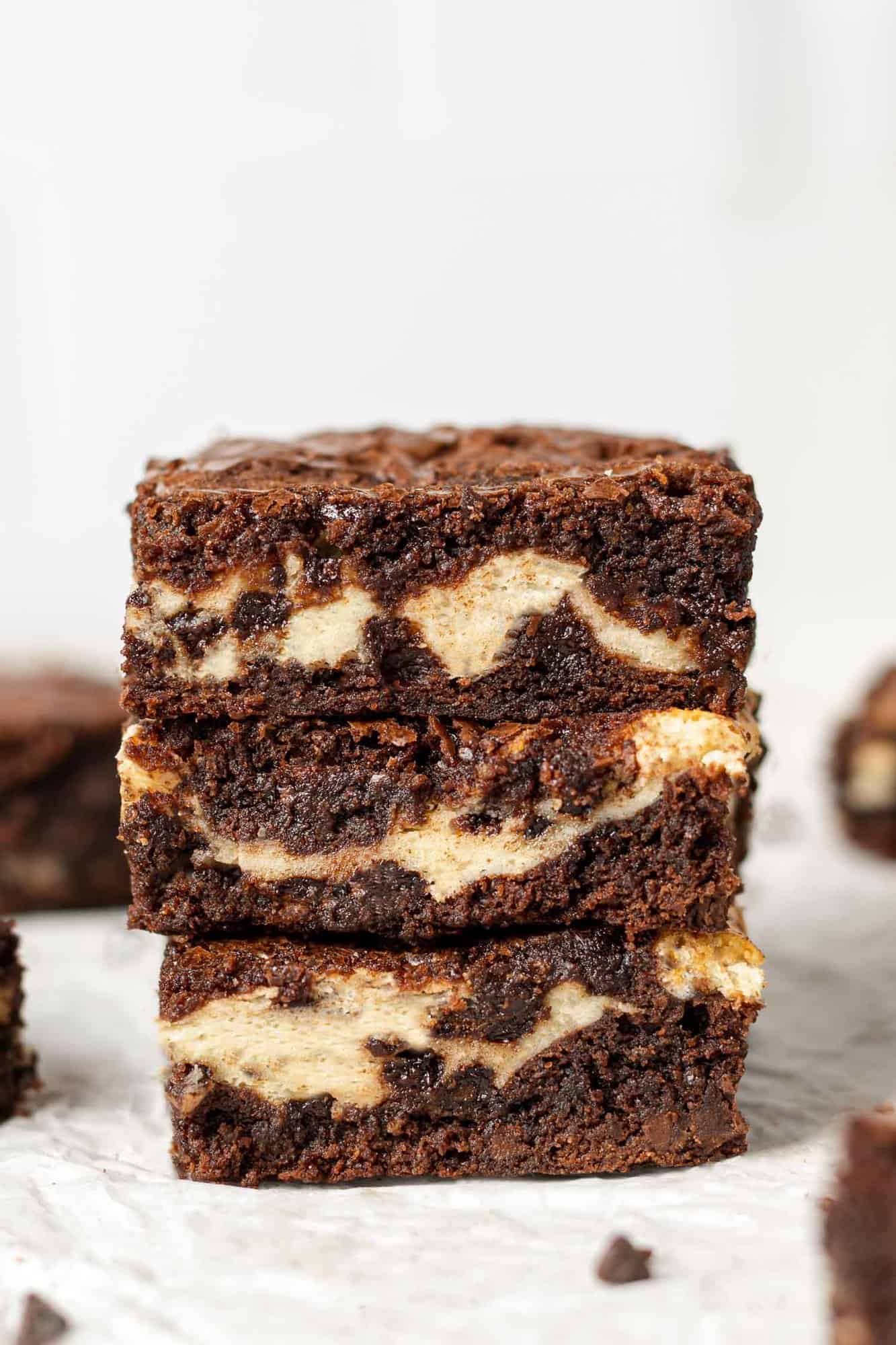 Stack of three brownies with cream cheese filling against a white background.