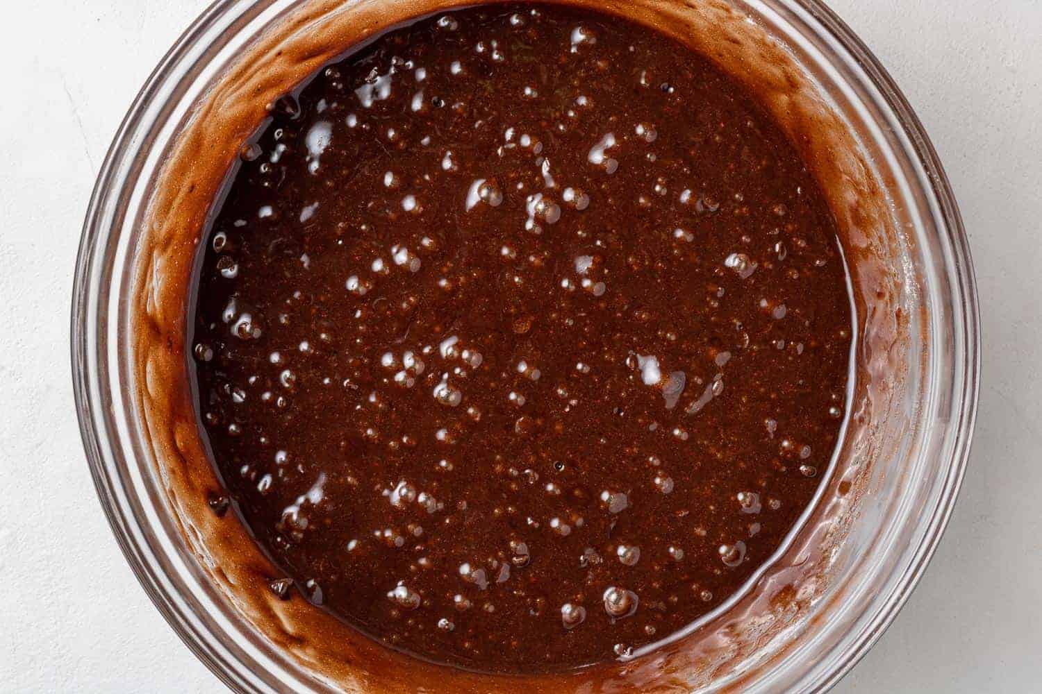 Brownie batter in clear glass bowl.