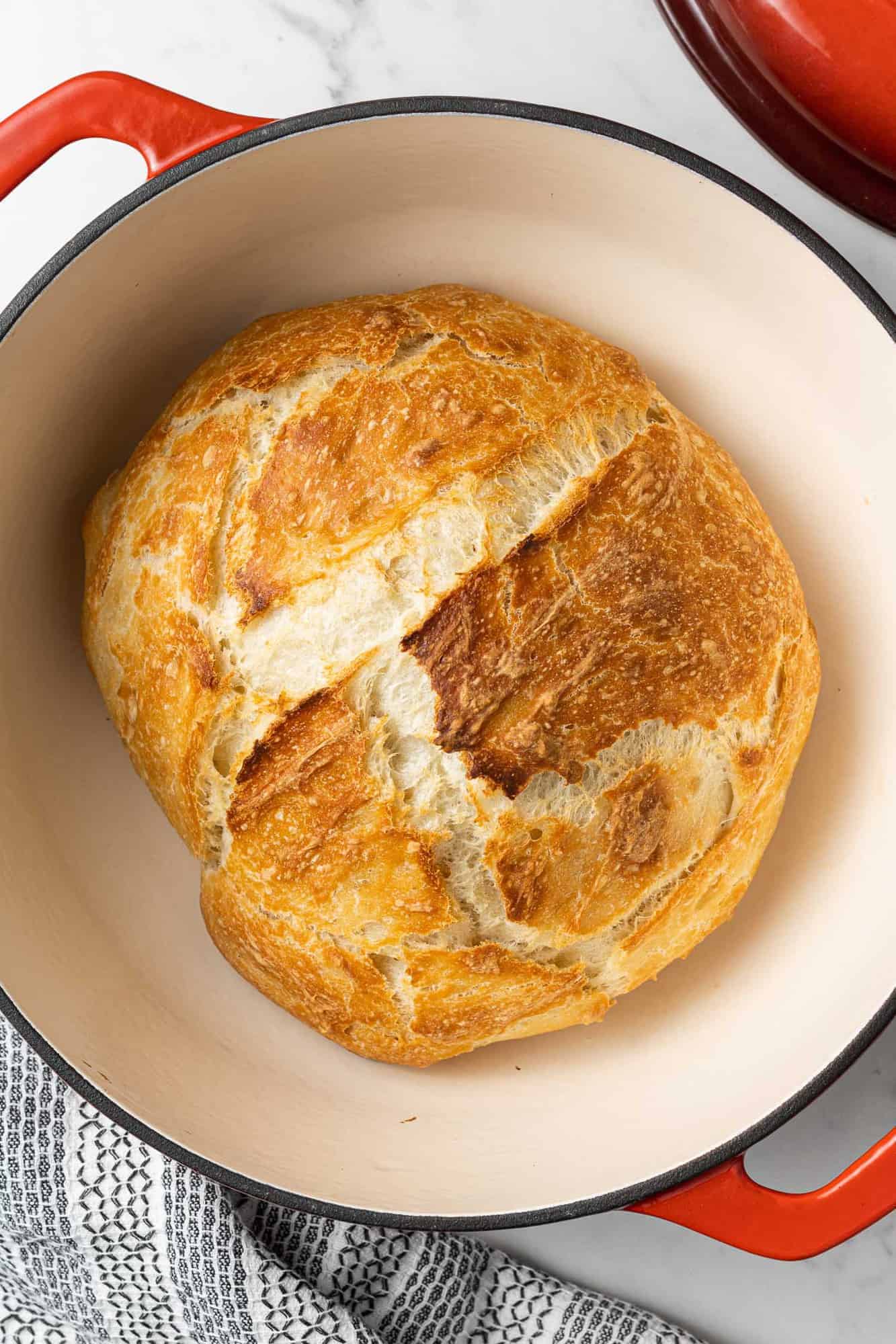 Overhead view of a baked loaf of bread in a dutch oven.