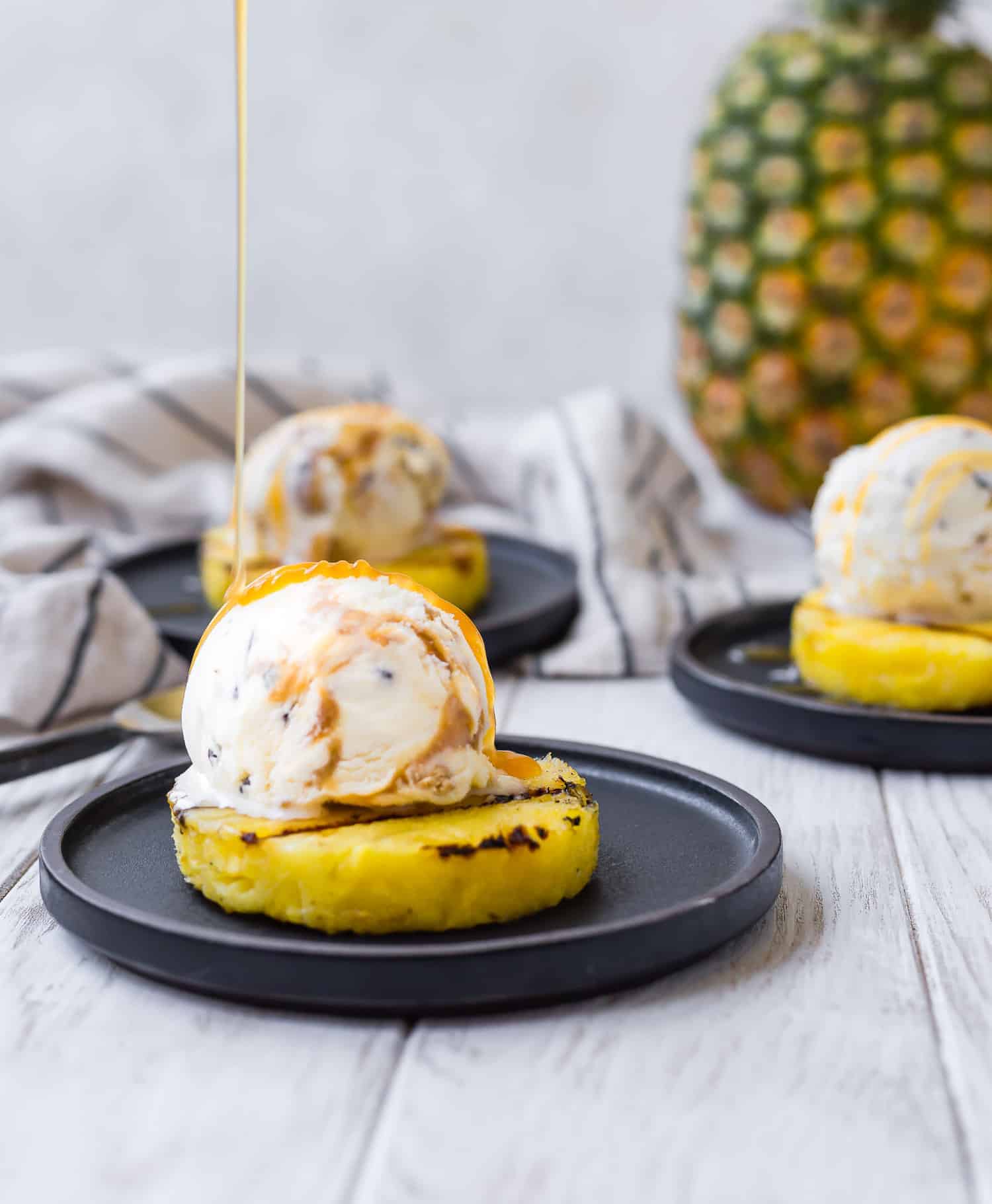 Caramel being drizzled on top of ice cream topped pineapple.