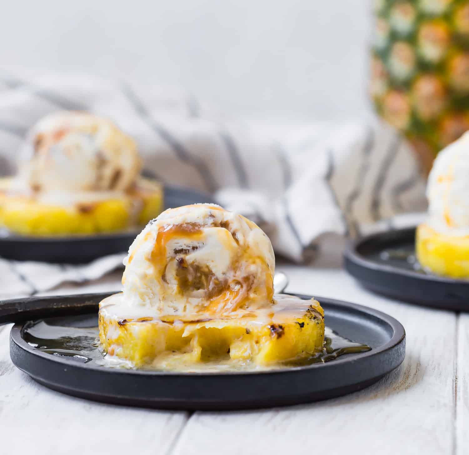 Pineapple and ice cream with a bite out of it to show caramel in ice cream.