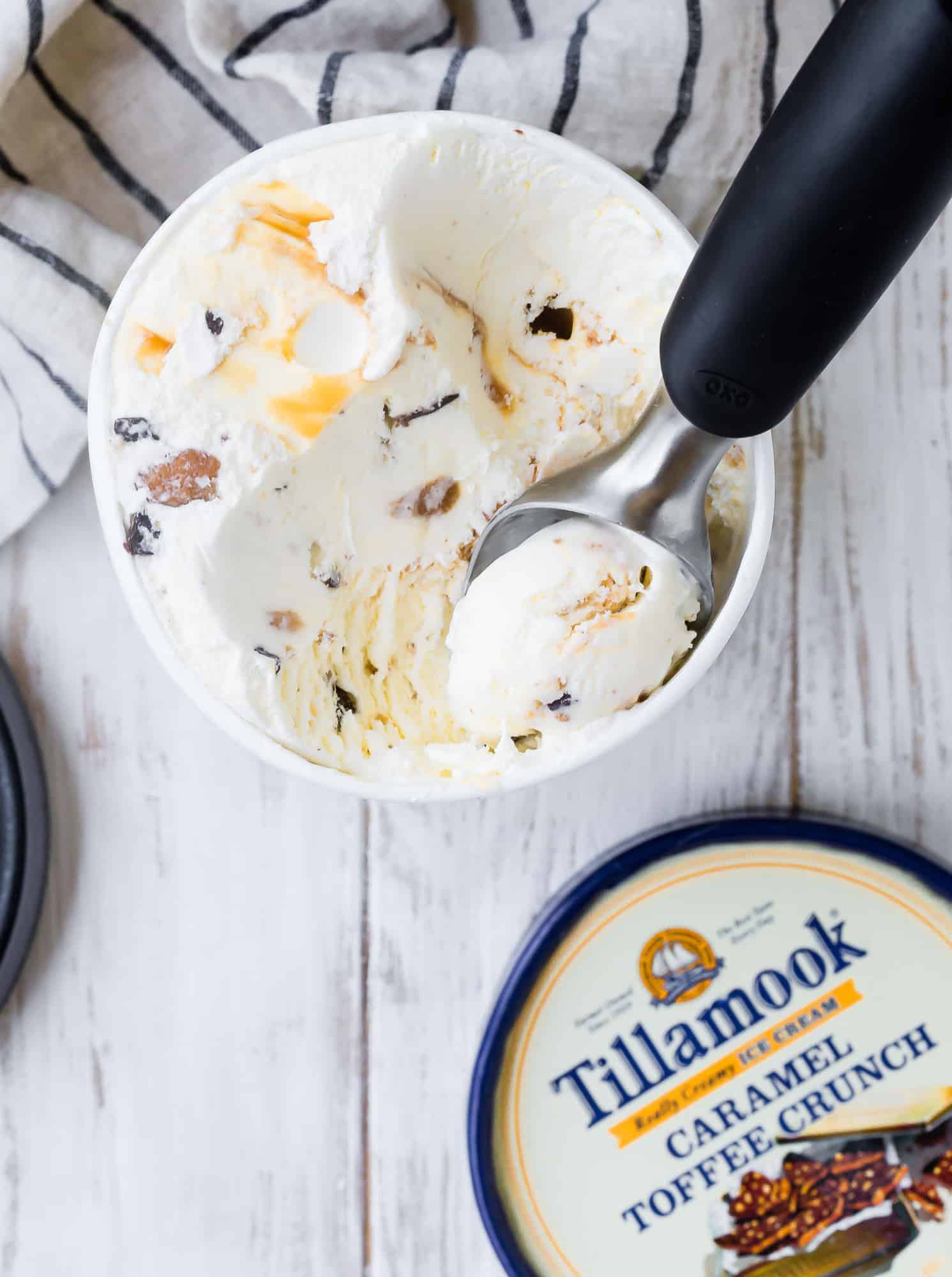 Ice cream being scooped out of a round cylinder carton.