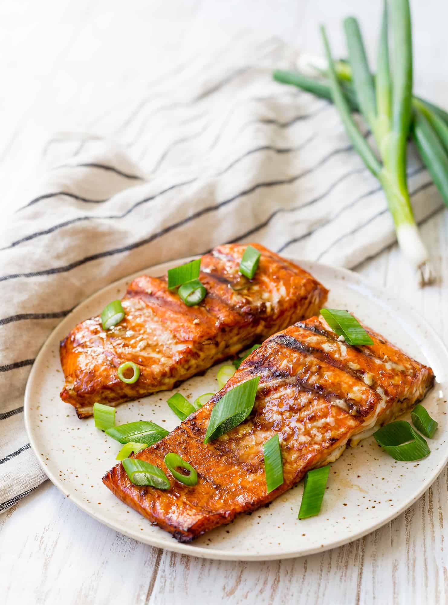 Two fillets of grilled salmon topped with green onion.