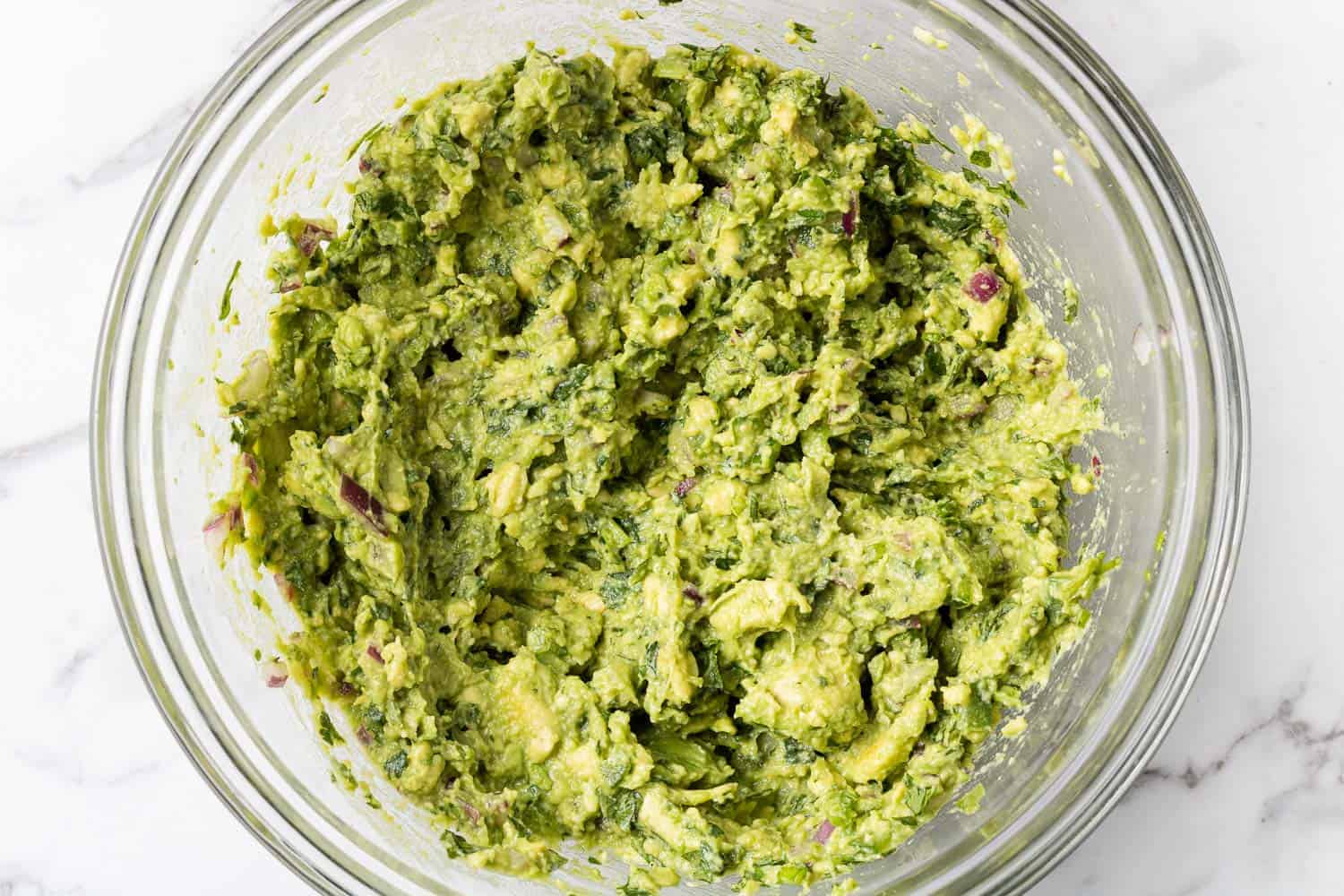 Guacamole in a clear glass mixing bowl.