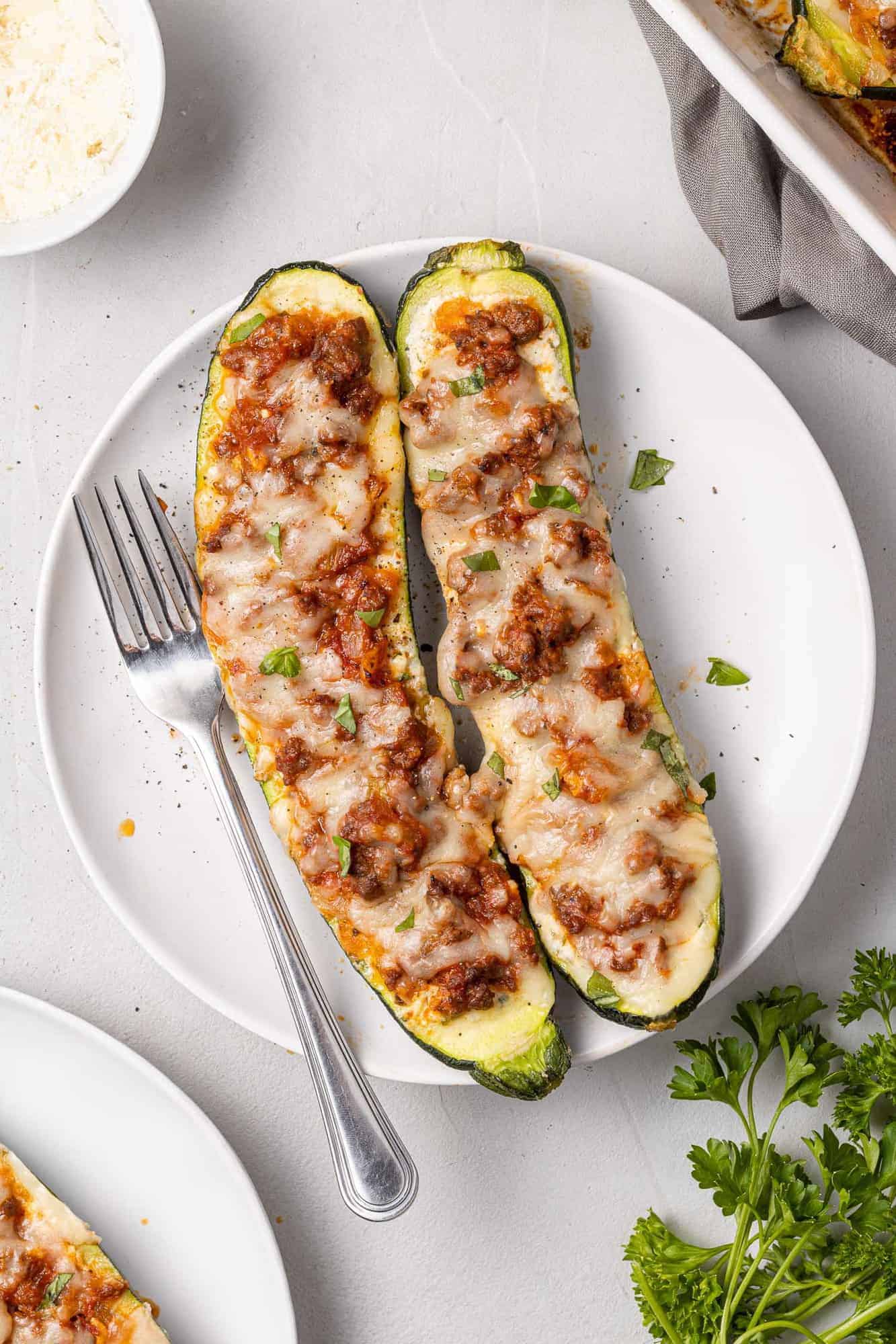 Two lasagna boats on a plate with a fork.