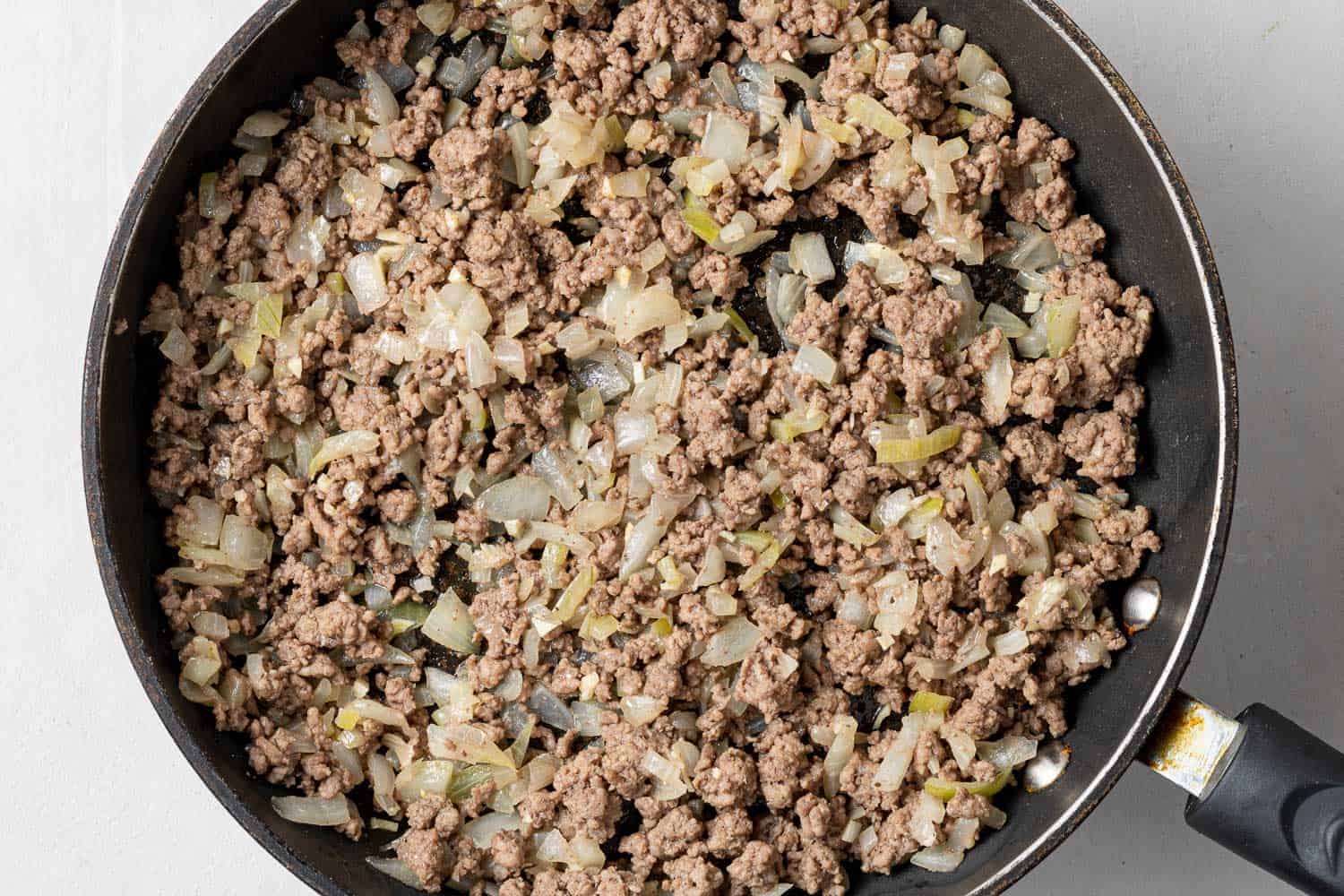 Browned ground meat and onions in a black skillet.