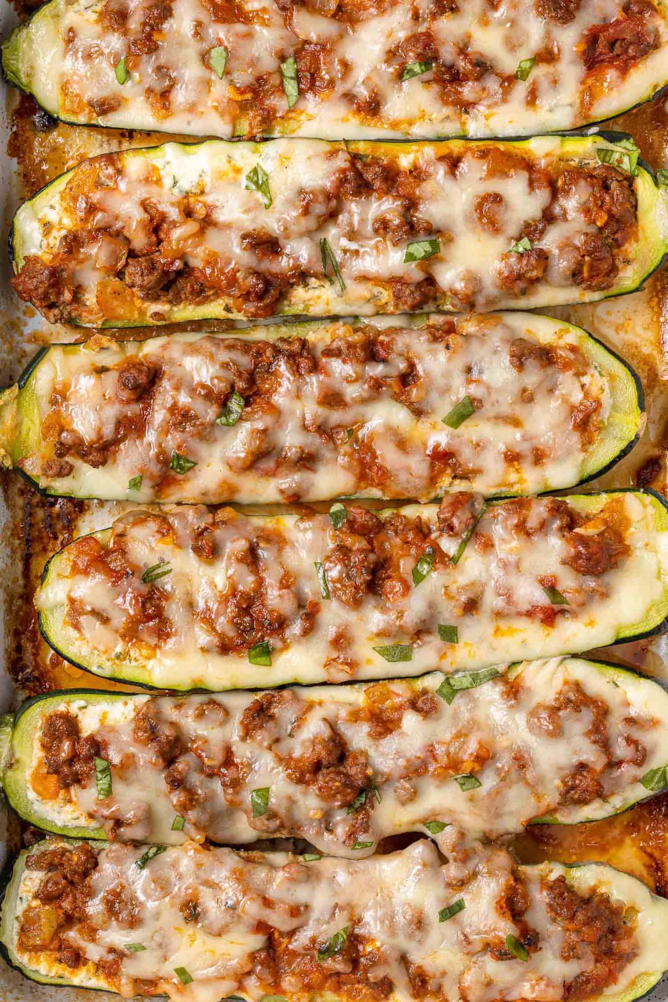 Overhead view of zucchini halves lined up and stuffed with ricotta and meat sauce.