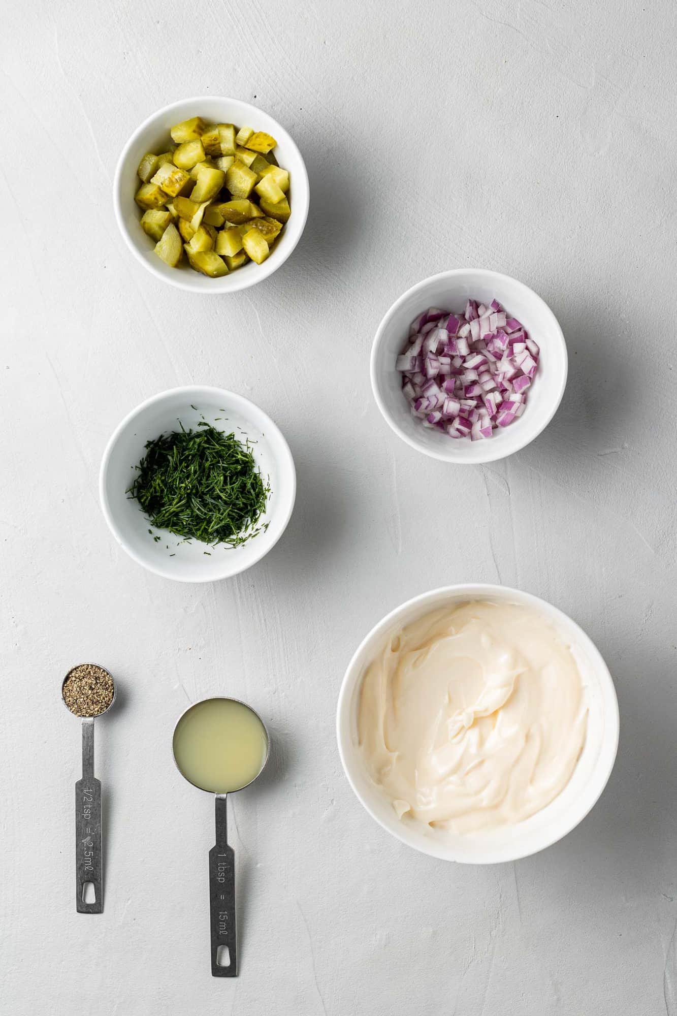 Overhead view of ingredients needed for recipe in small white bowls and measuring spoons.