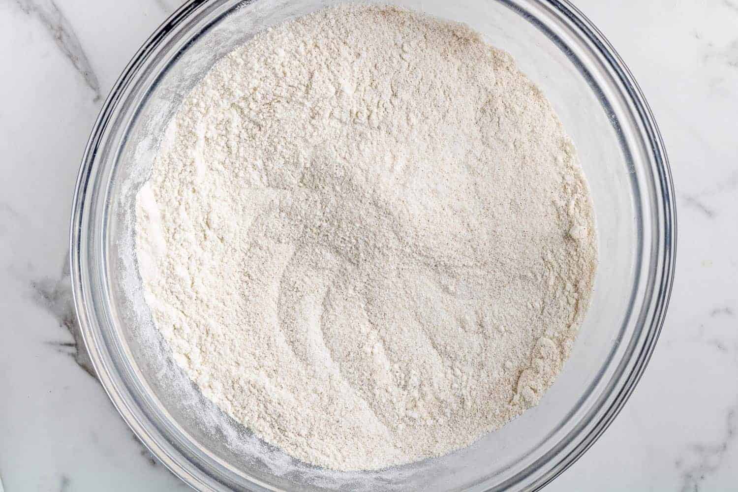 Dry ingredients in a clear glass mixing bowl.