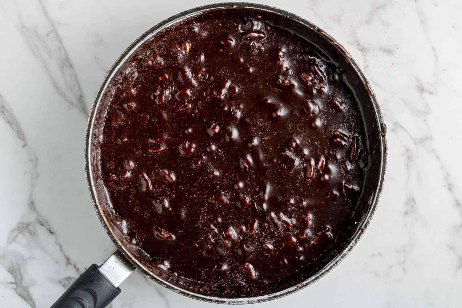 Chocolate frosting with pecans in a saucepan.