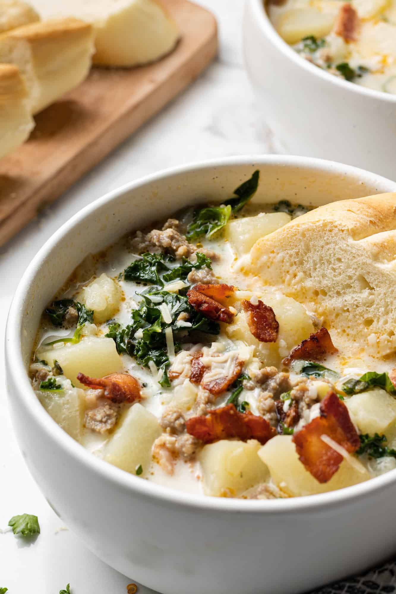 Bowl of soup in a white bowl, with a piece of bread dipped in.