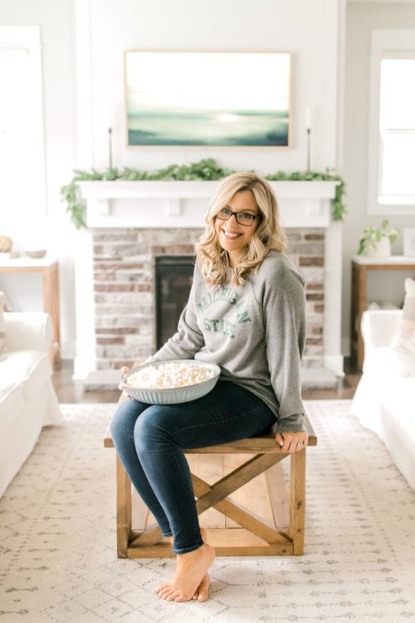 Rachel Cooks founder, Rachel Gurk sitting on a table with a bowl of popcorn.