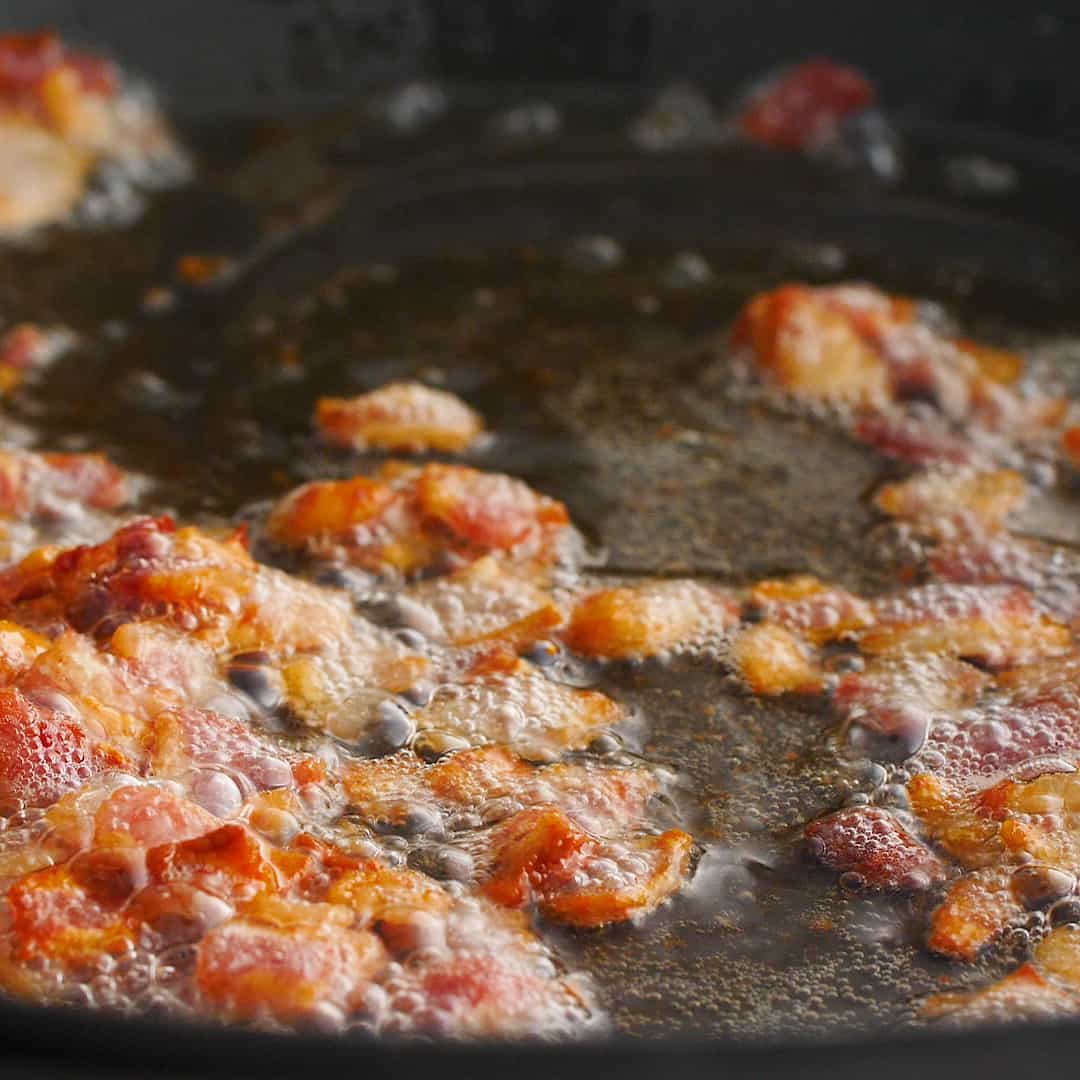 Pancetta cooking in a black pan.