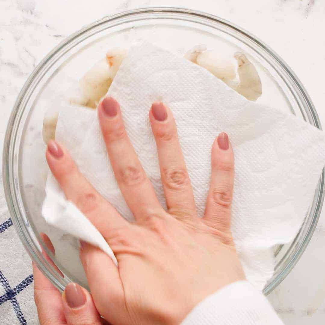 Shrimp being patted dry with a paper towel.