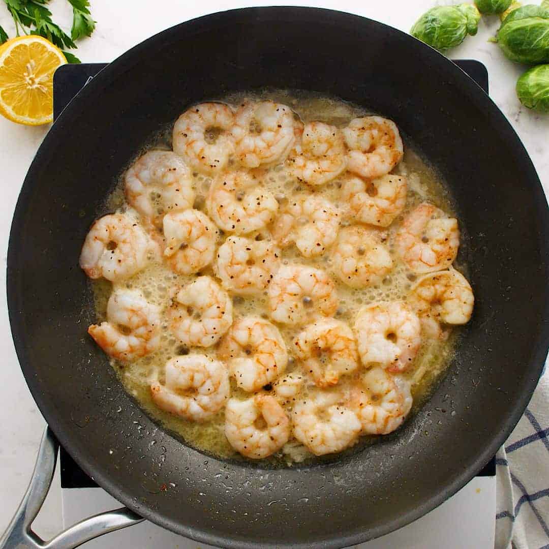 Cooked shrimp in a black skillet.