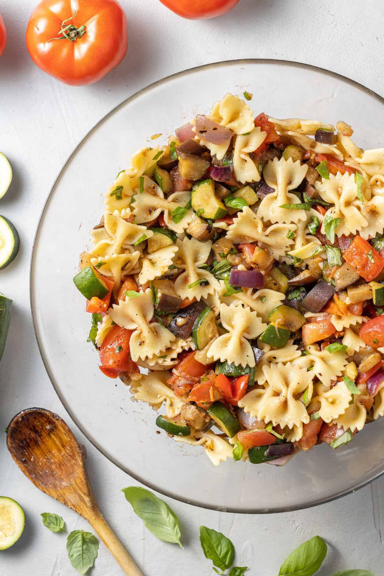 Pasta salad in a clear glass mixing bowl.