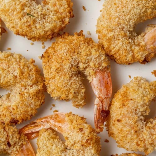 Breaded shrimp in a single layer on a white background.