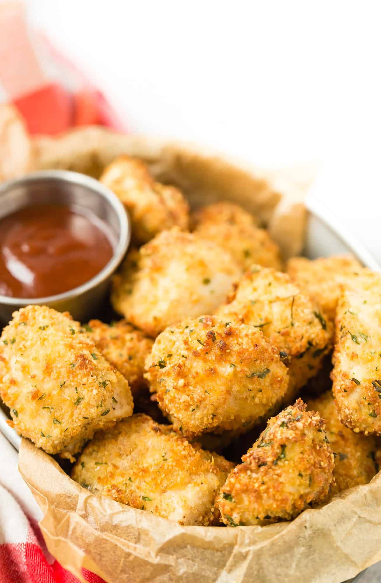 Breaded chicken nuggets in a metal basket lined with brown parchment paper.