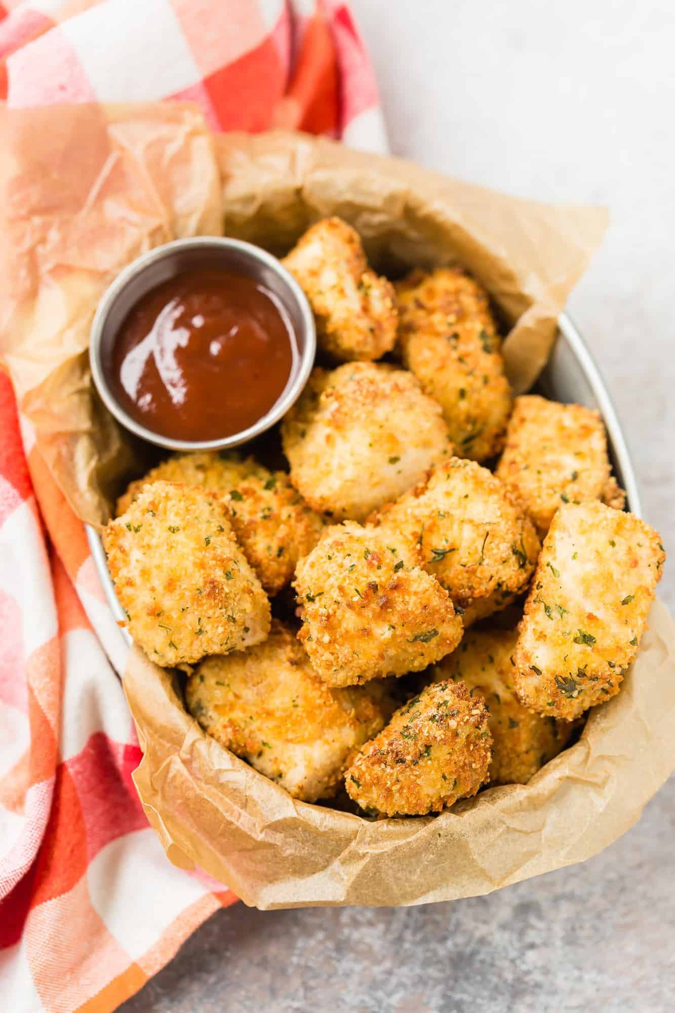 Overhead view of chicken nuggets in a basket with barbecue sauce.