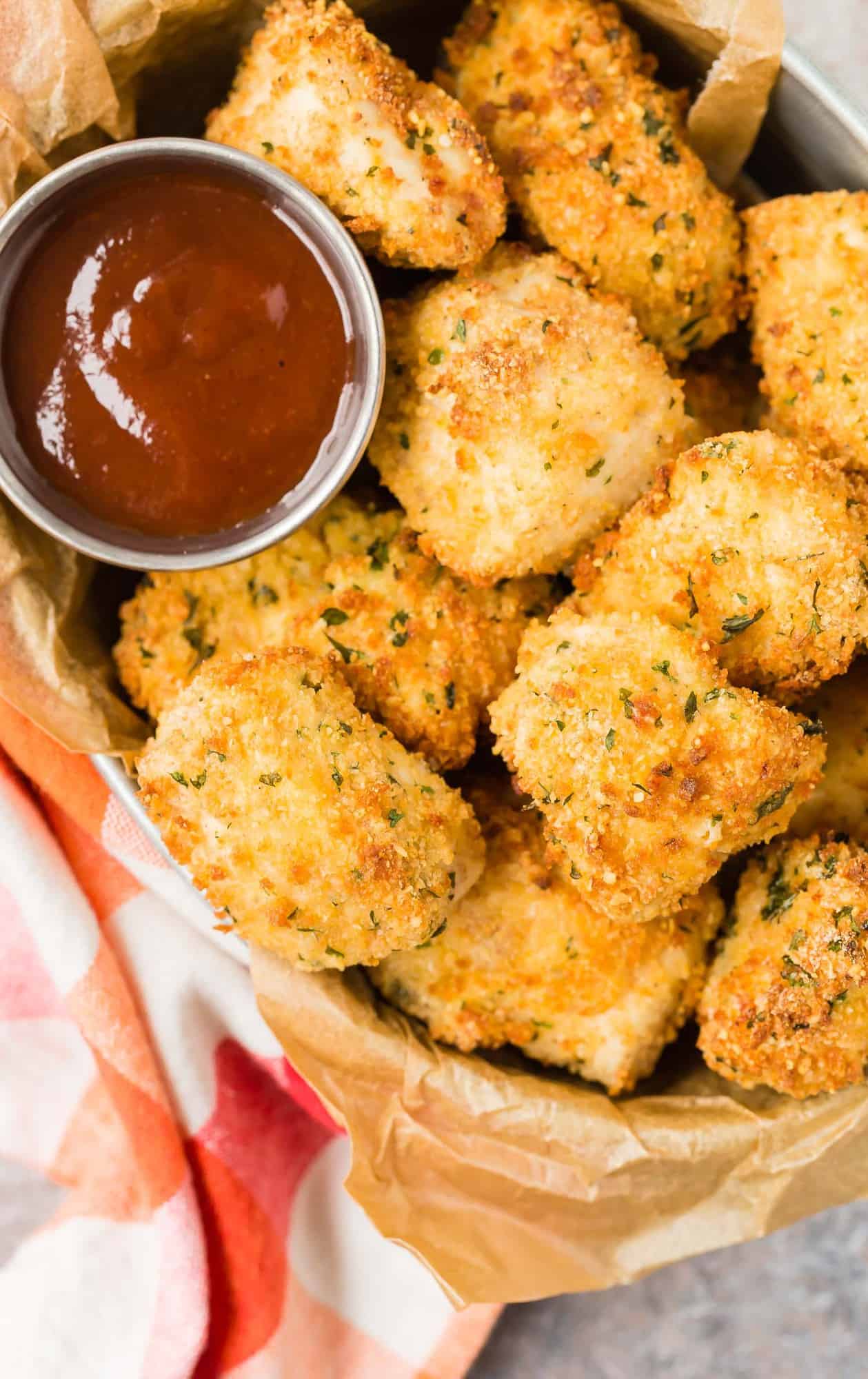 Chicken nuggets in a metal basket lined with parchment paper.