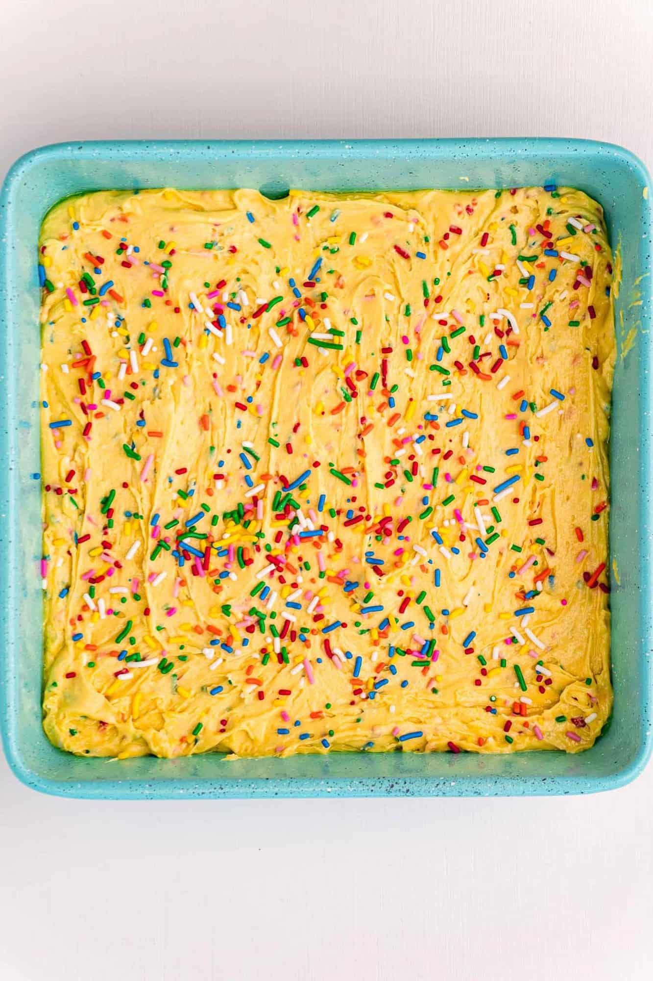 Unbaked blondies in a bright blue square baking dish.