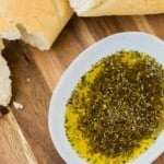 Overhead view of bread dipping oil and bread on a wooden surface.