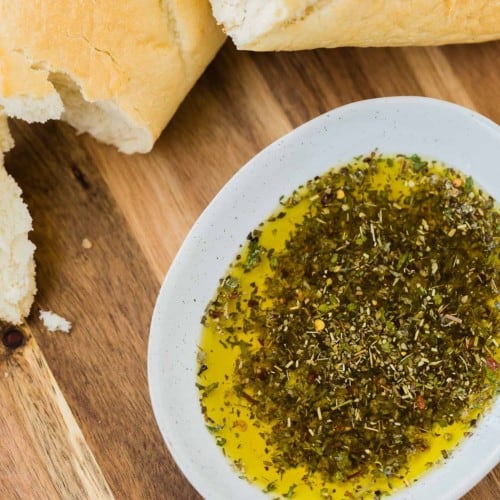 Overhead view of bread dipping oil and bread on a wooden surface.