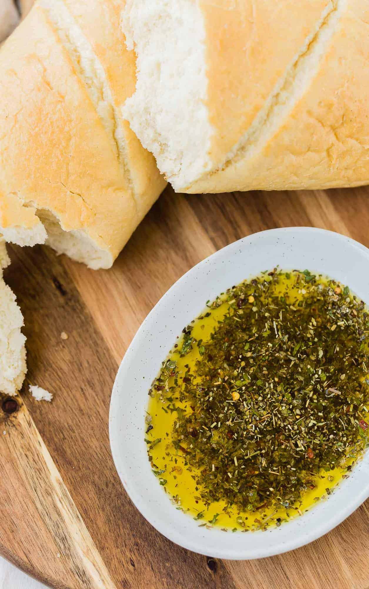 Overhead view of bread dipping oil and bread on a wooden surface.