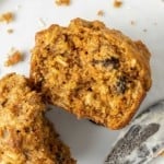 Carrot muffin split open to show texture and contents, including raisins and oats.