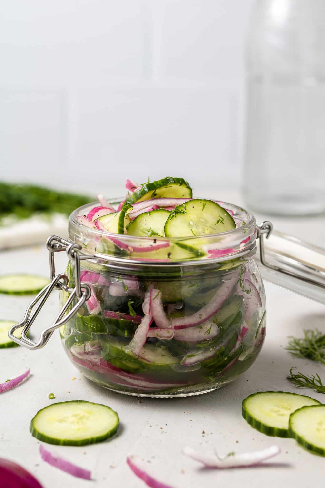 Jar filled with sliced cucumbers and onions in a brine.