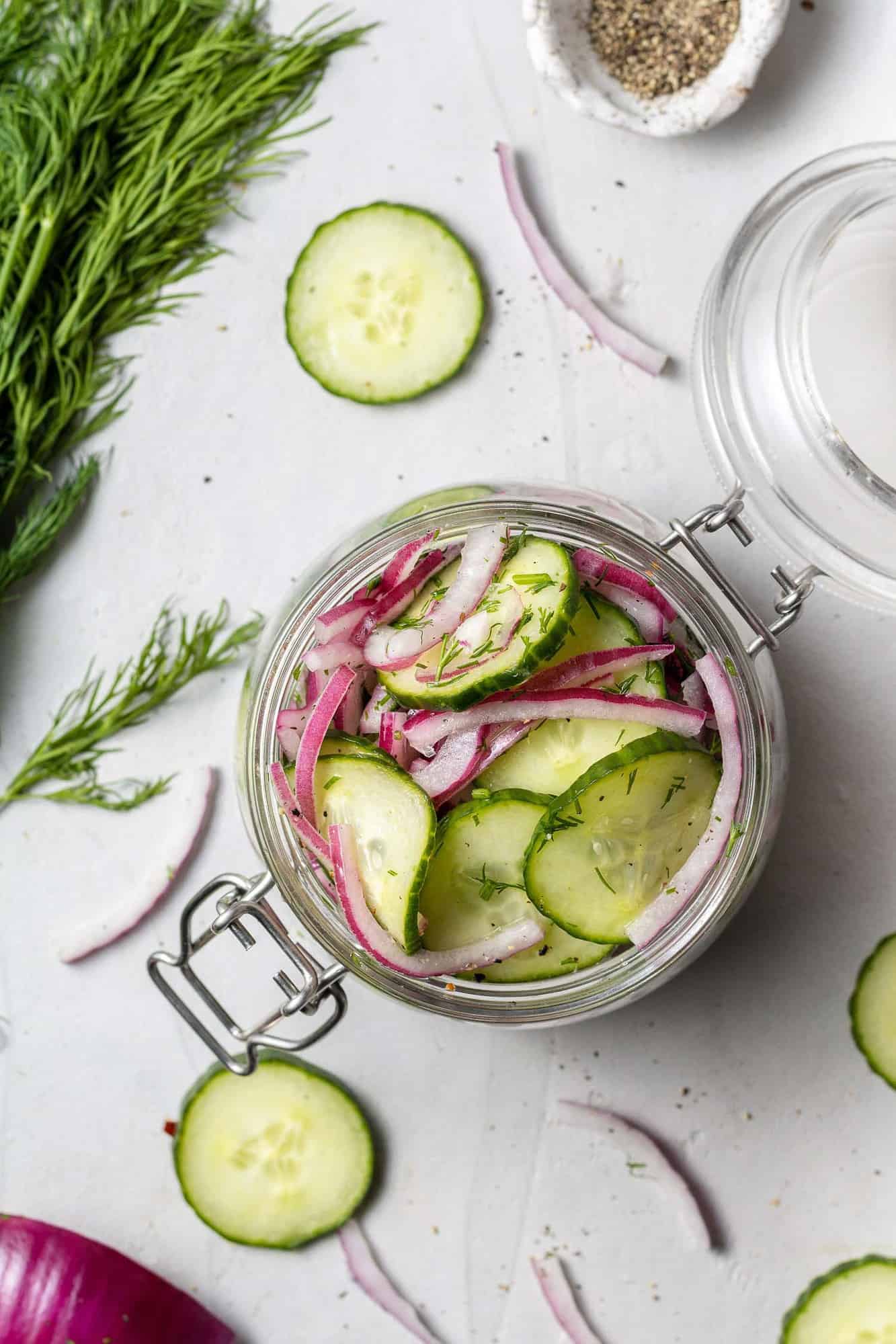 Overhead view of cucumbers and onions in a small glass jar.