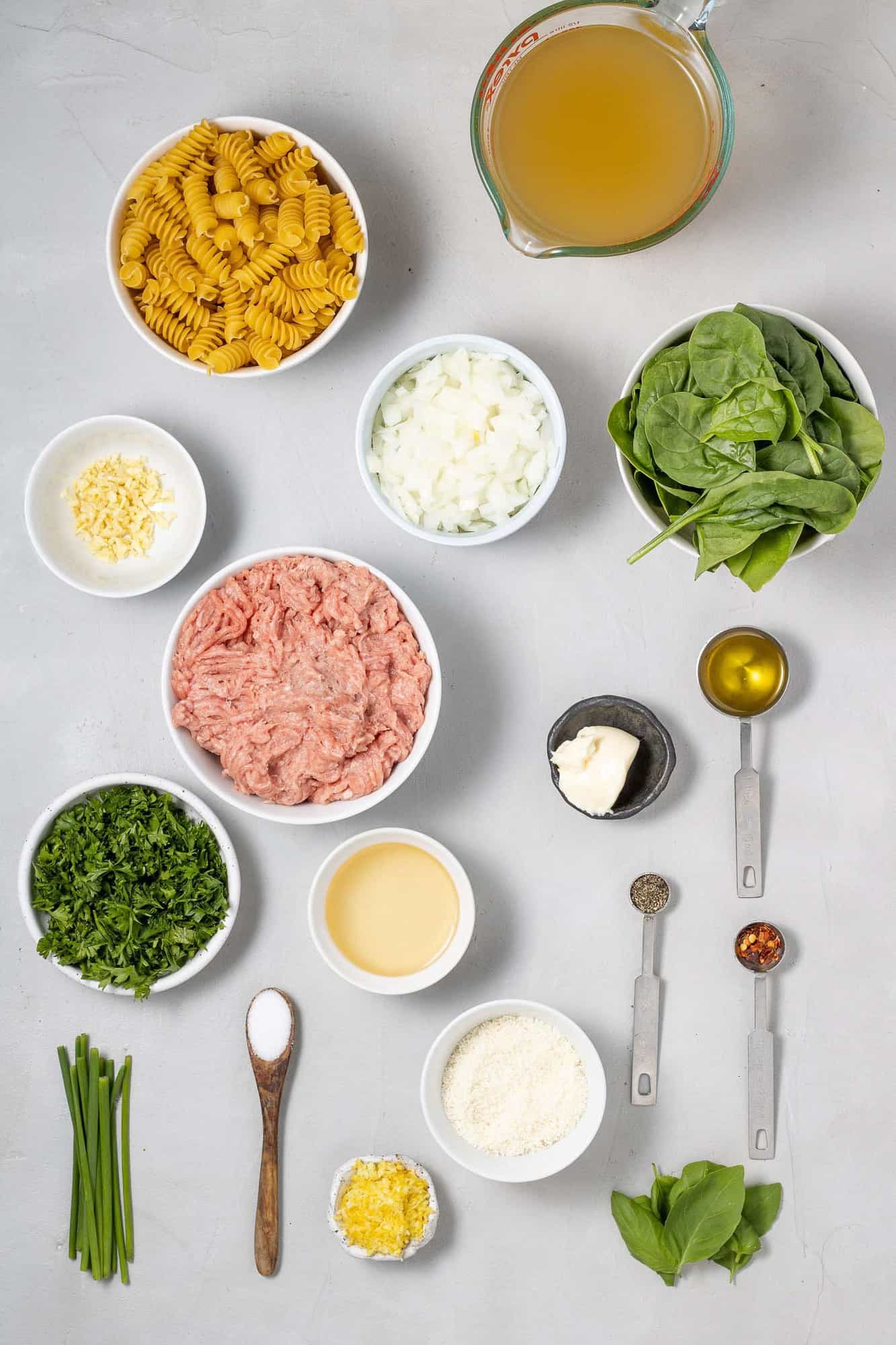 Overhead view of ingredients needed for recipe, including ground chicken, spinach, and lemon.