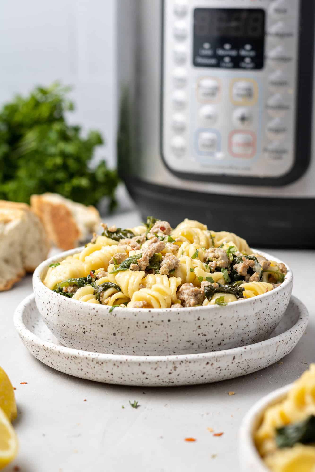 Bowl of instant pot lemon pasta with an instant pot in background.