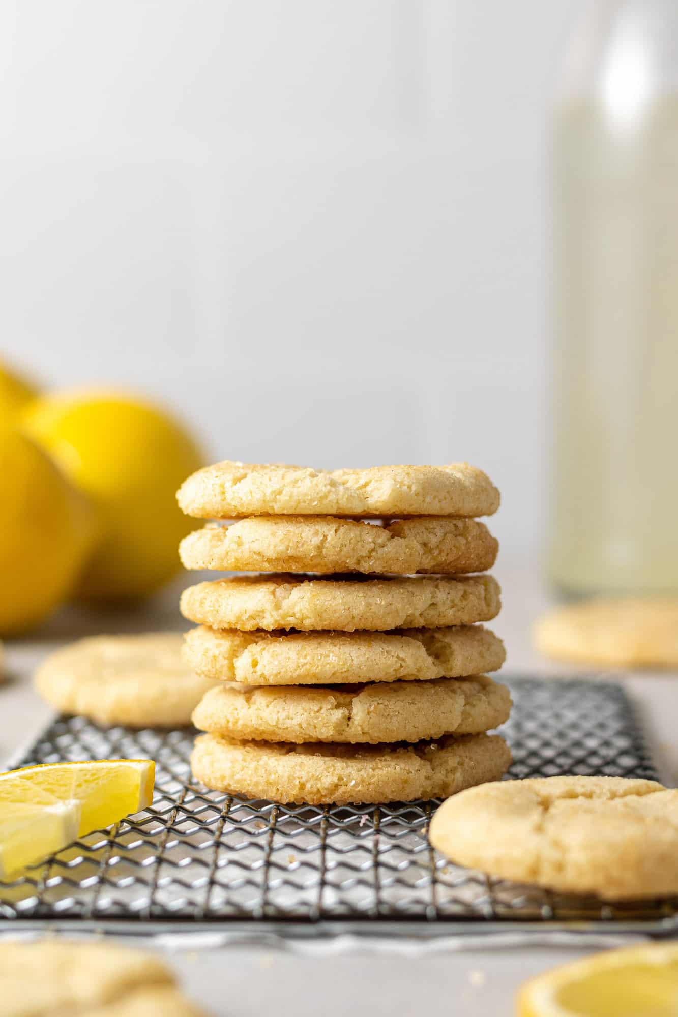 Lemon sugar cookies in a tall stack on wiring baking rack.