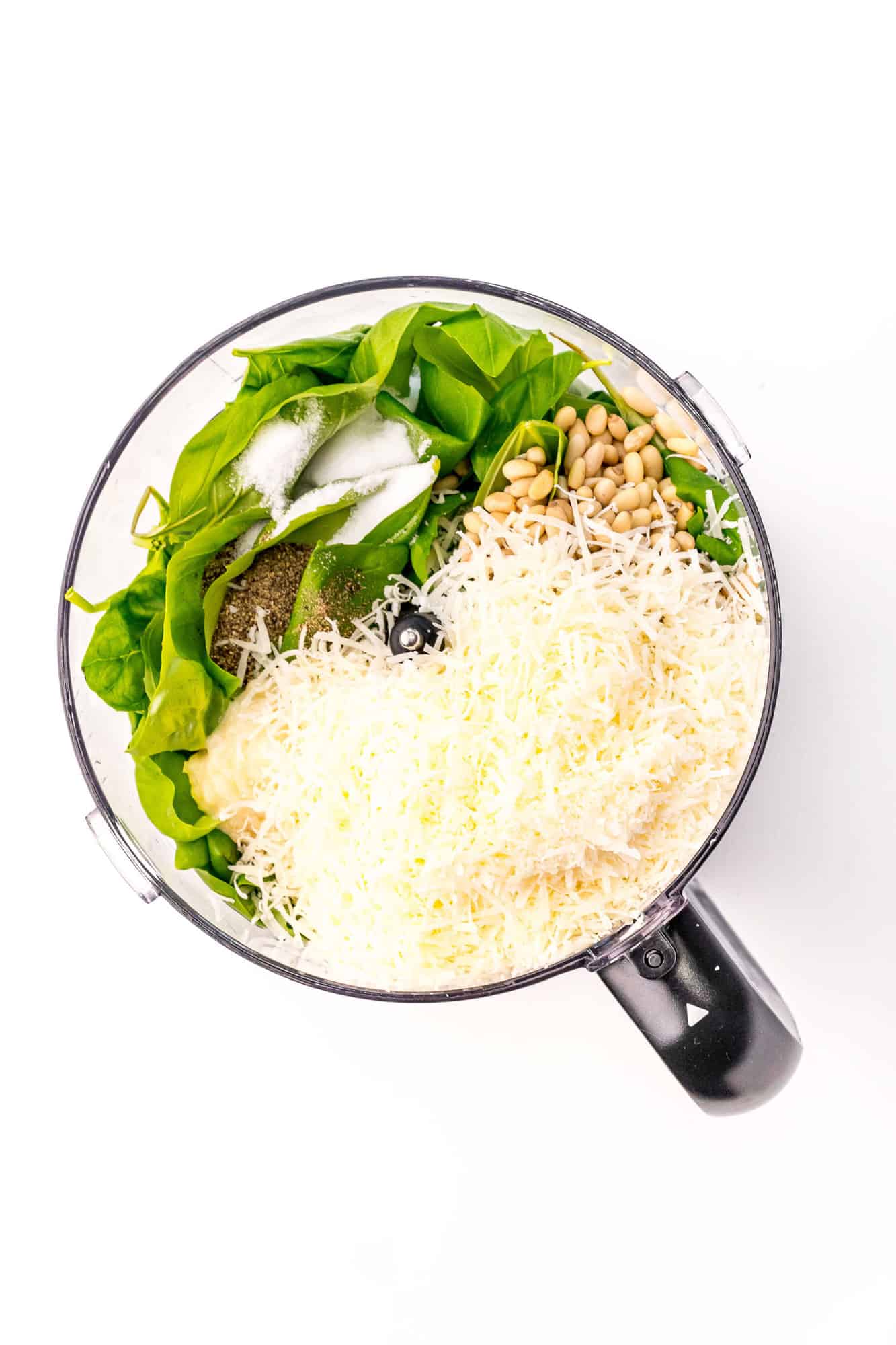 Pesto ingredients in a food processor bowl.