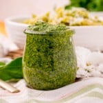 Straight on view of pesto in a glass jar.
