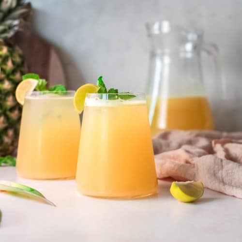 Light yellow drink with a pineapple in the background.