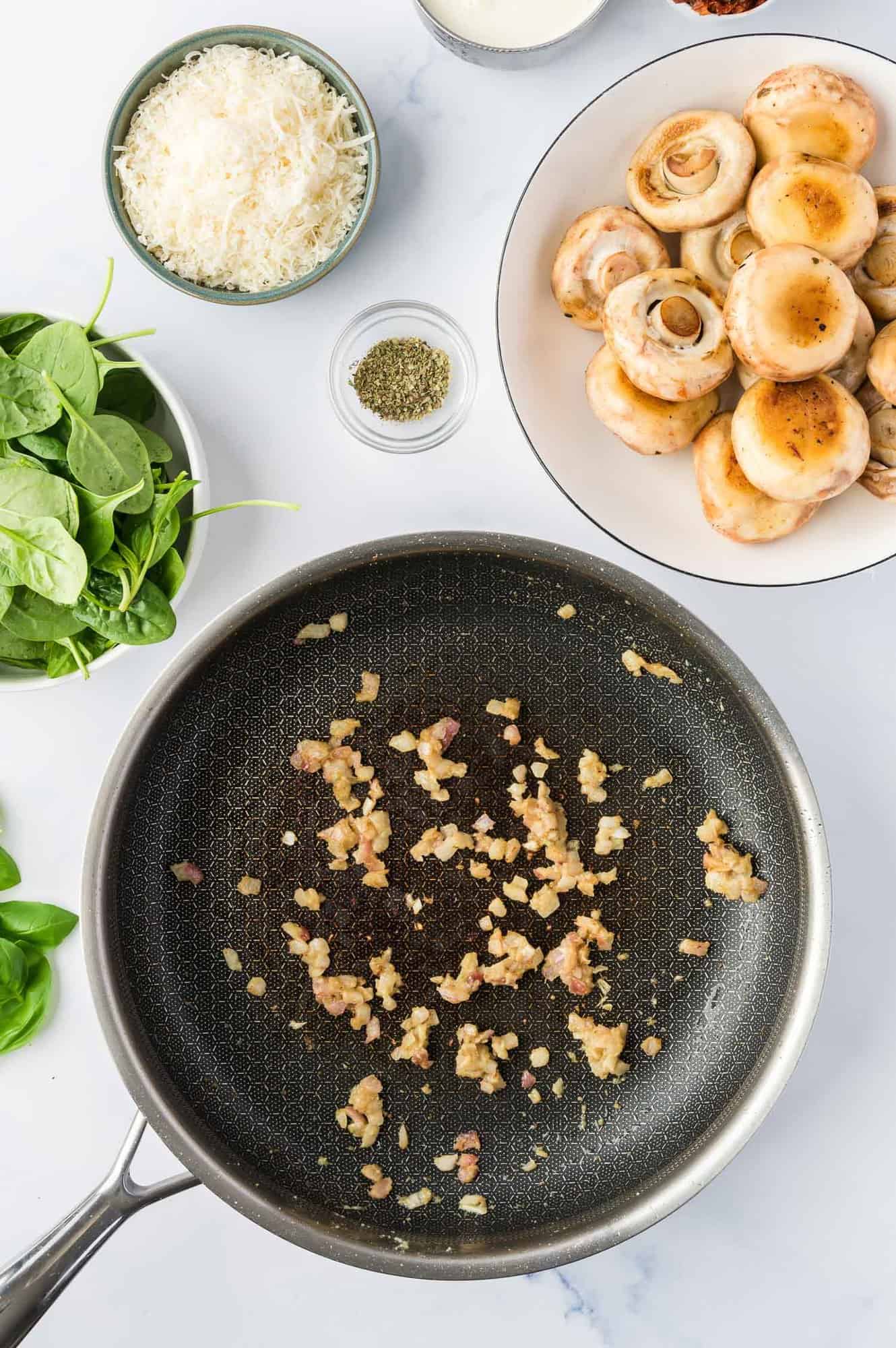 Minced onion and garlic in a black saute pan.