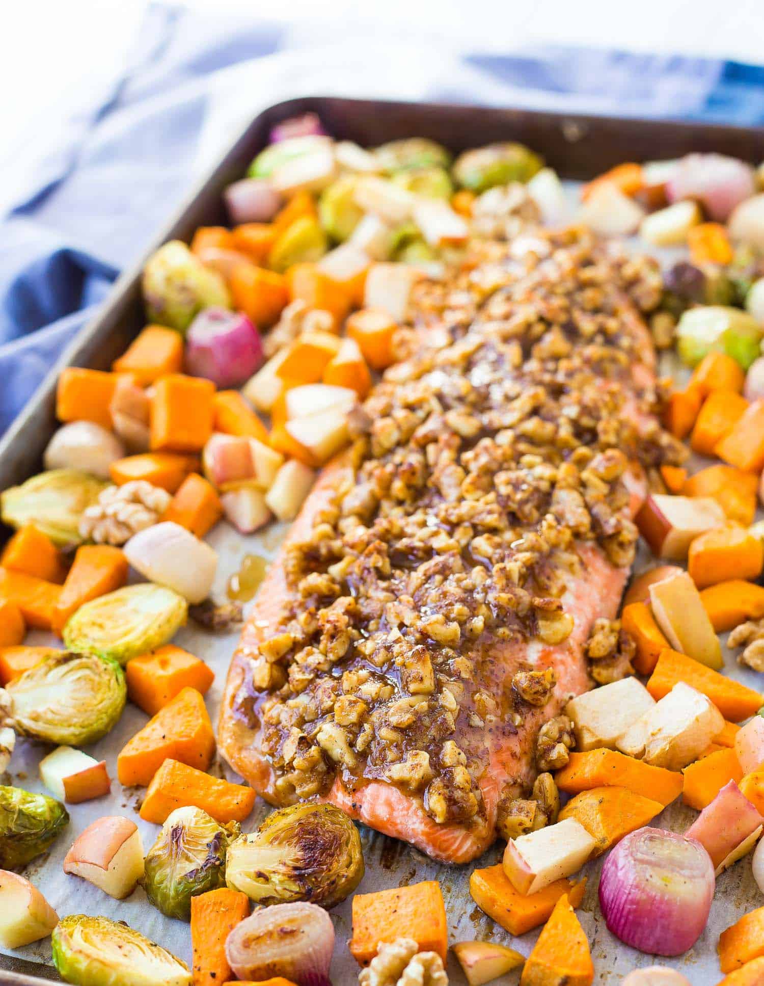 Salmon with maple syrup walnut topping, on a sheet pan with sweet potatoes, apples, shallots, brussels sprouts.