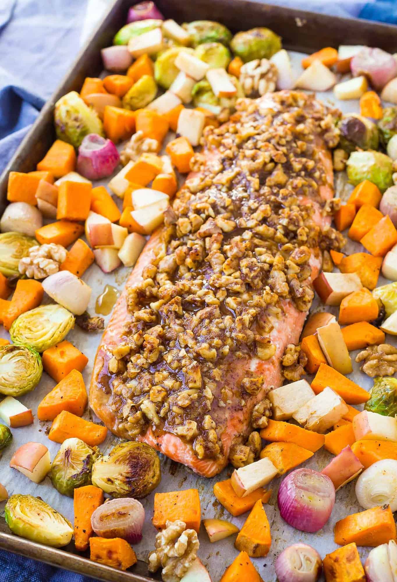 Salmon topped with walnuts and surrounded with colorful vegetables.