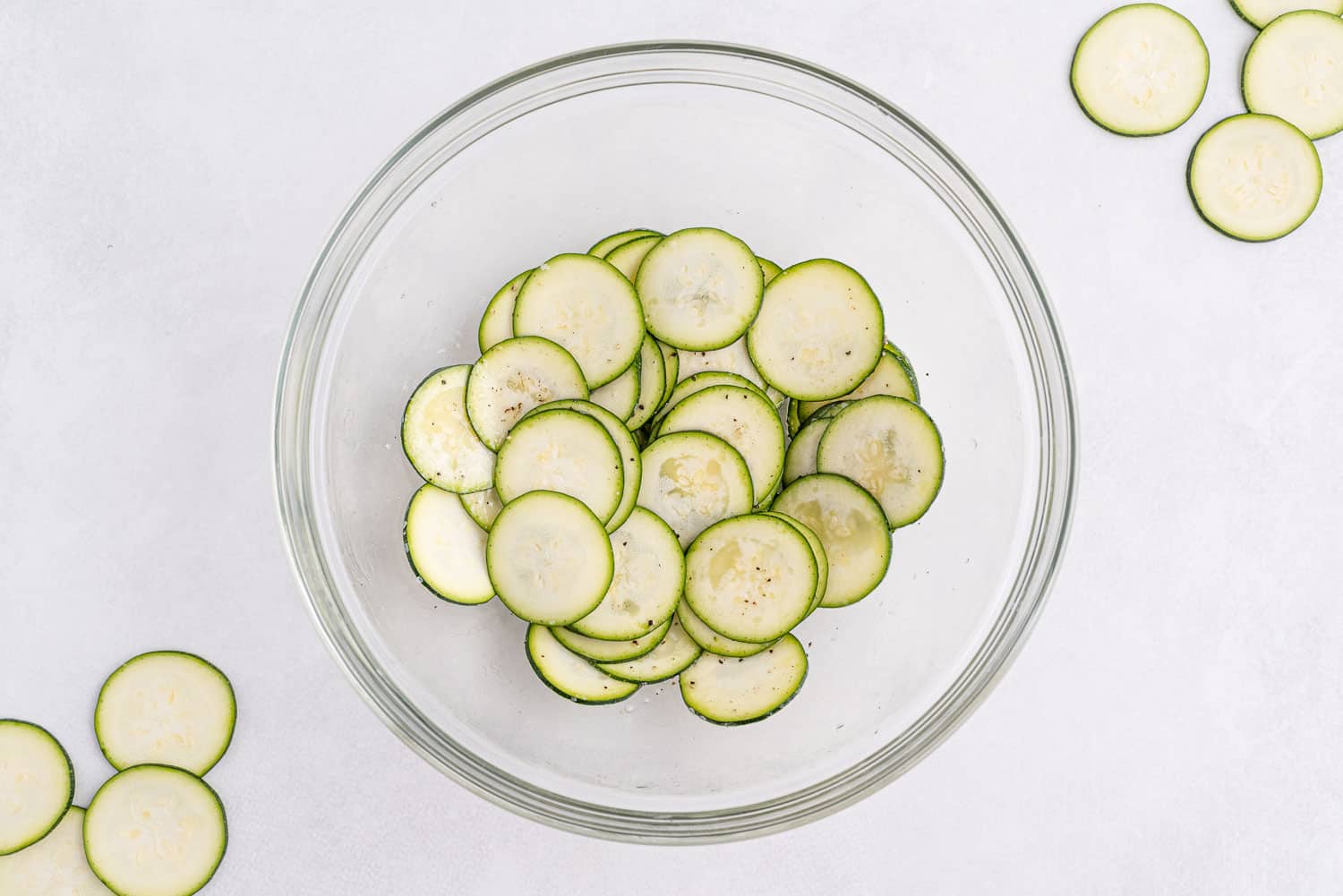 Zucchini slices in a large glass bowl on a white background.