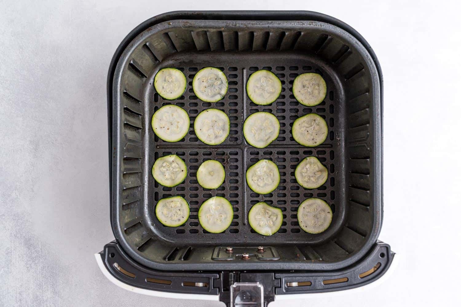 Zucchini in the basket of an air fryer.