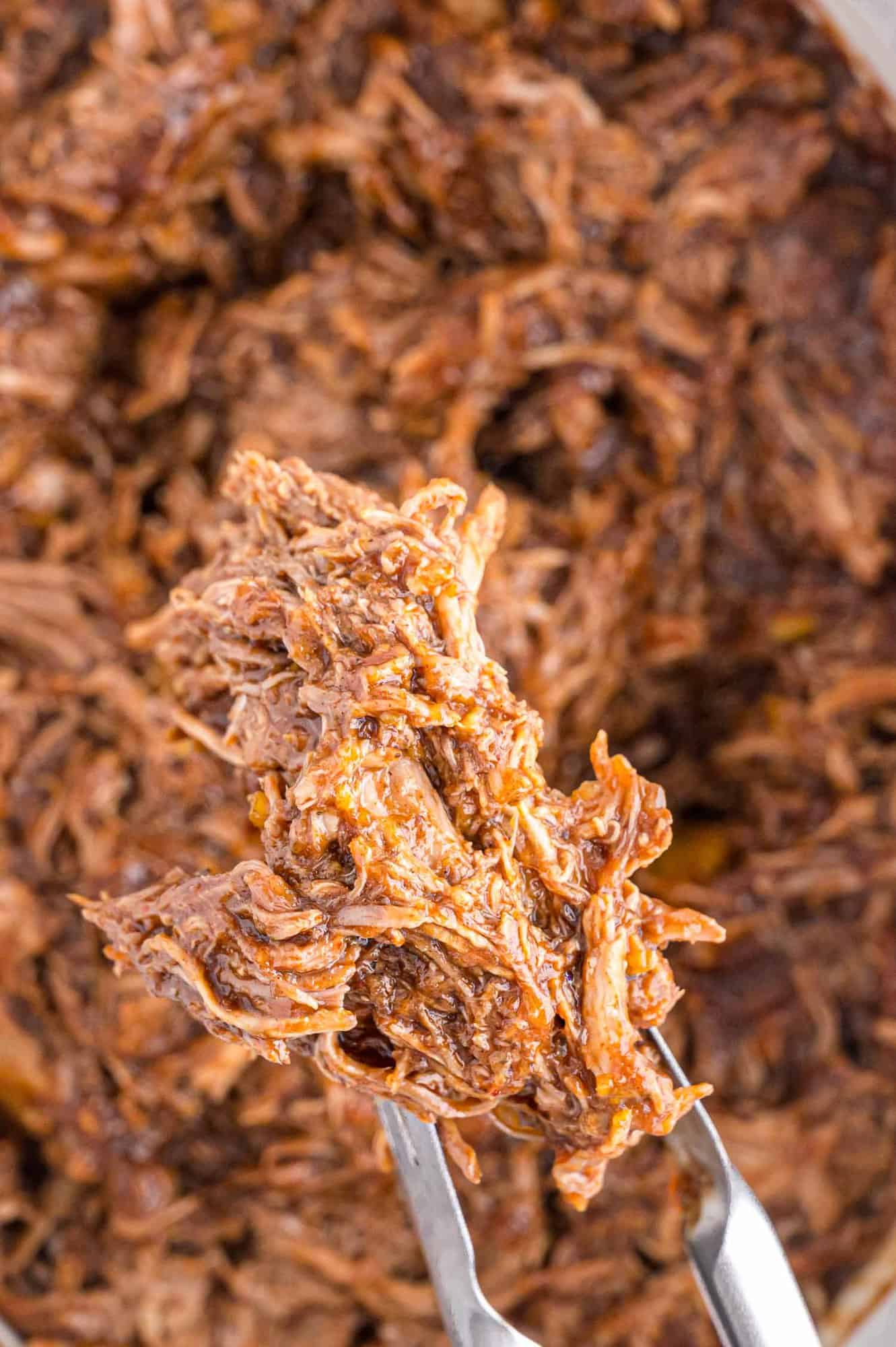 Pulled pork on tongs.