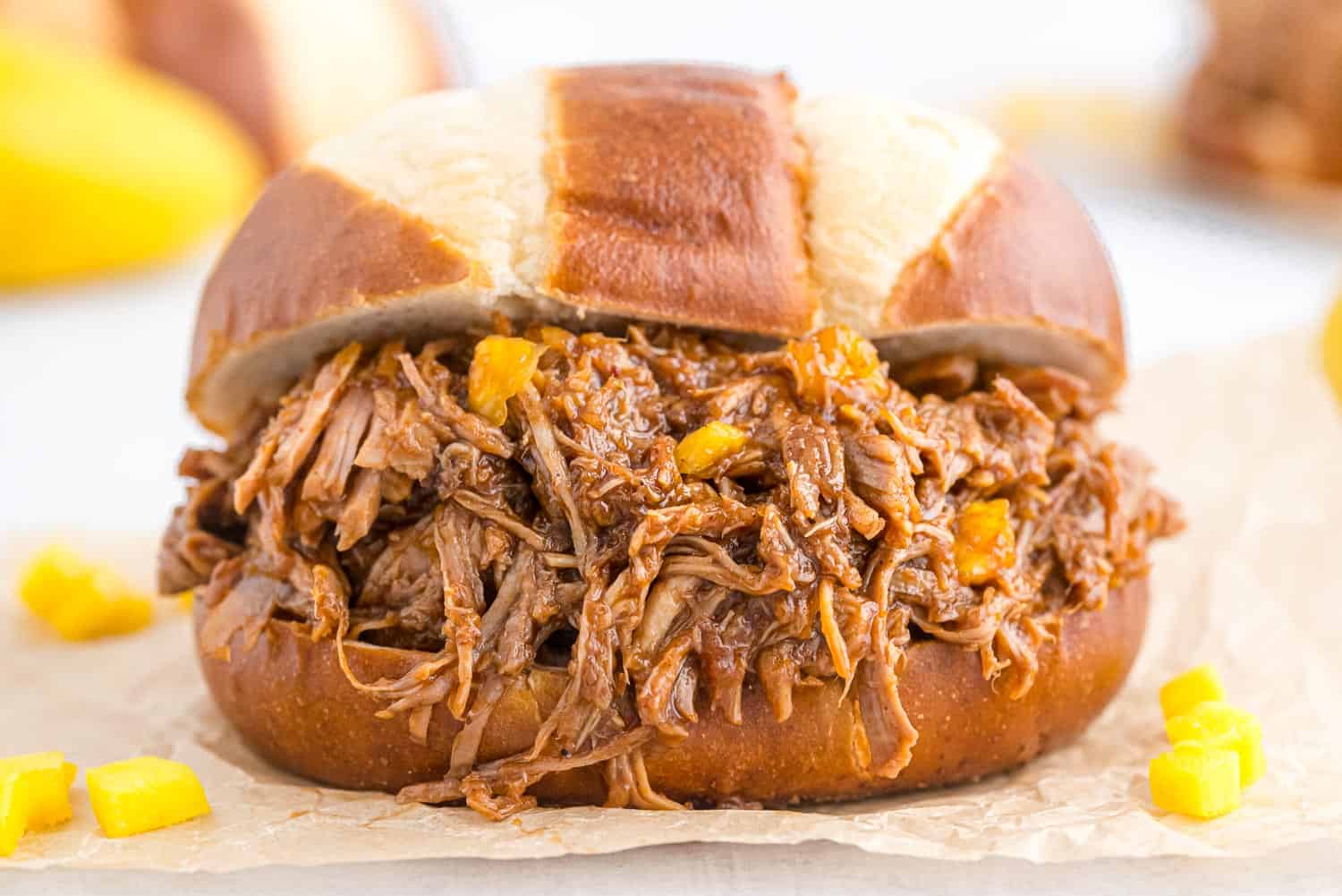 Pulled pork spilling out of a pretzel bun.