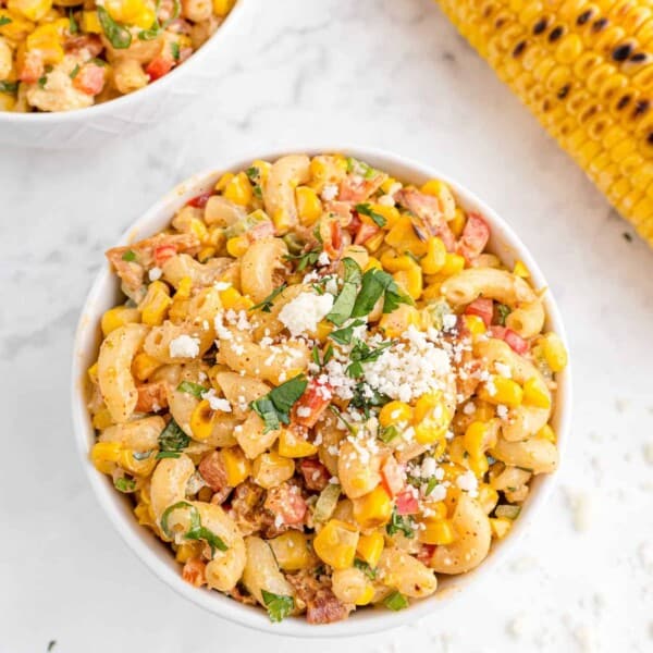 Overhead view of round bowl of pasta salad with macaroni, corn, red peppers, cotija, and cilantro.