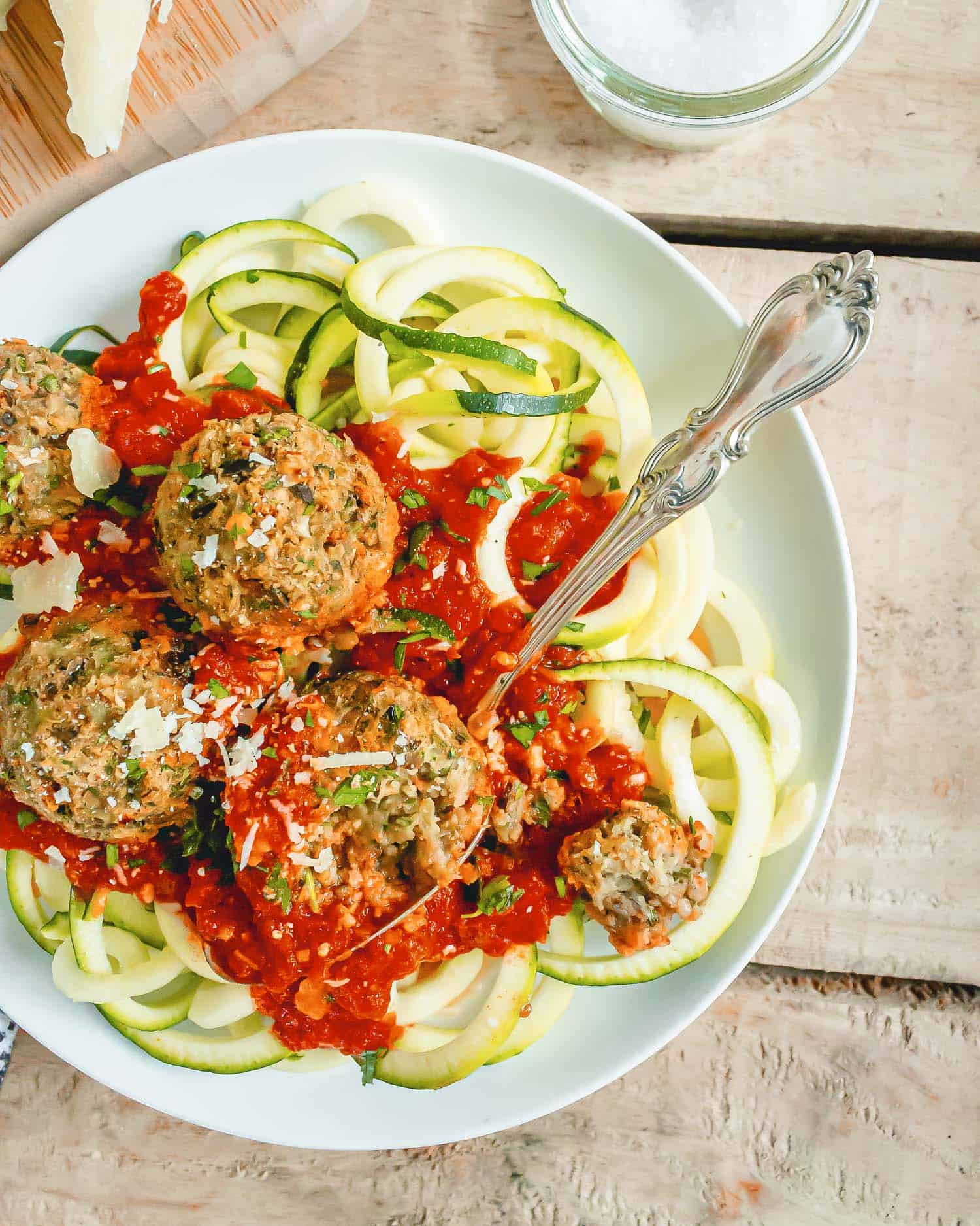 Overhead view of meatballs atop zucchini noodles, with spaghetti sauce.